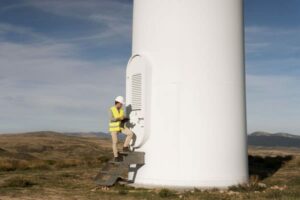 technicien de maintenance éolien devant une éolienne