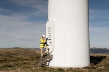 technicien de maintenance éolien devant une éolienne